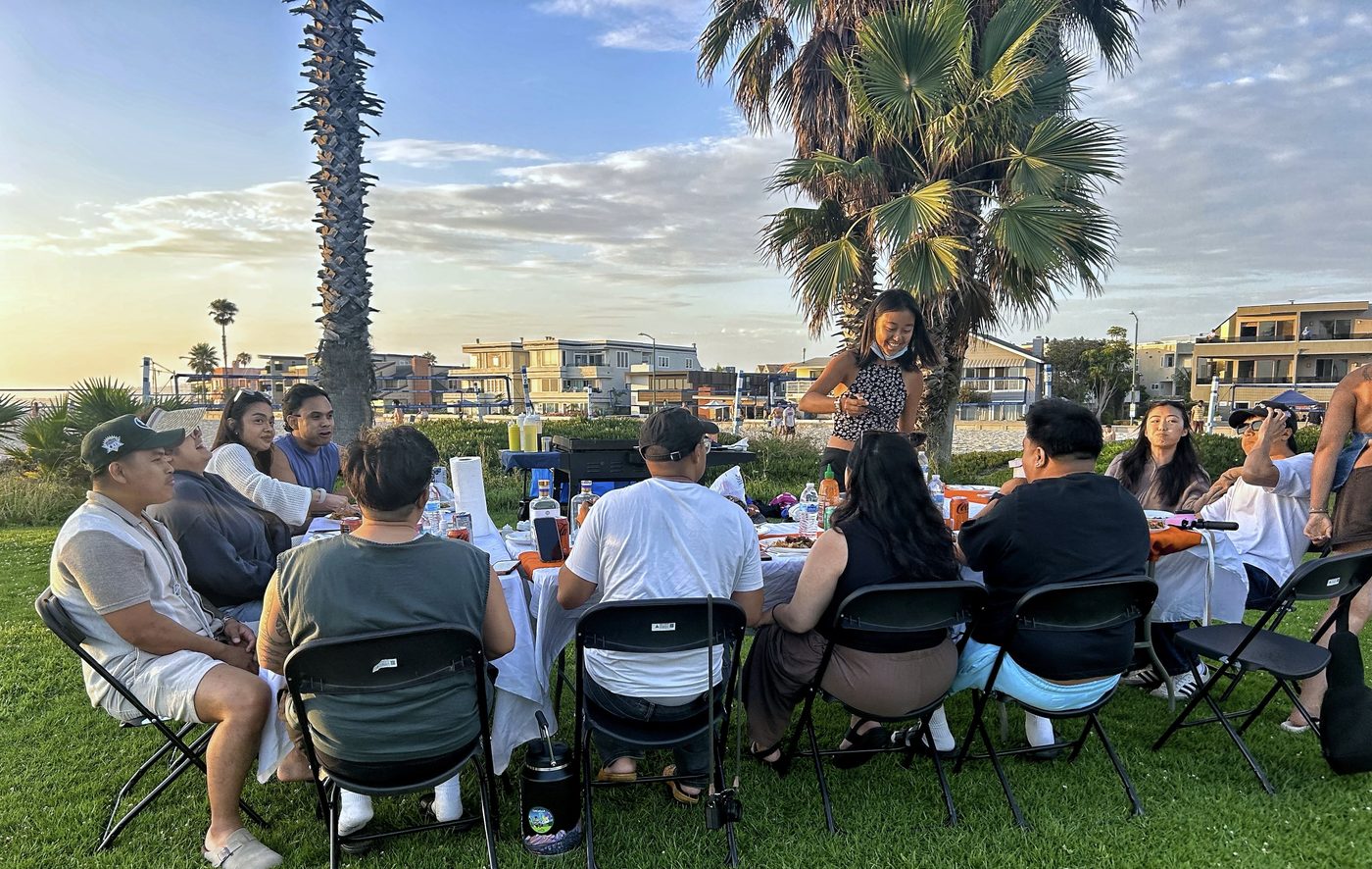 Long table hibachi dinner on the grass at the beach at sunset